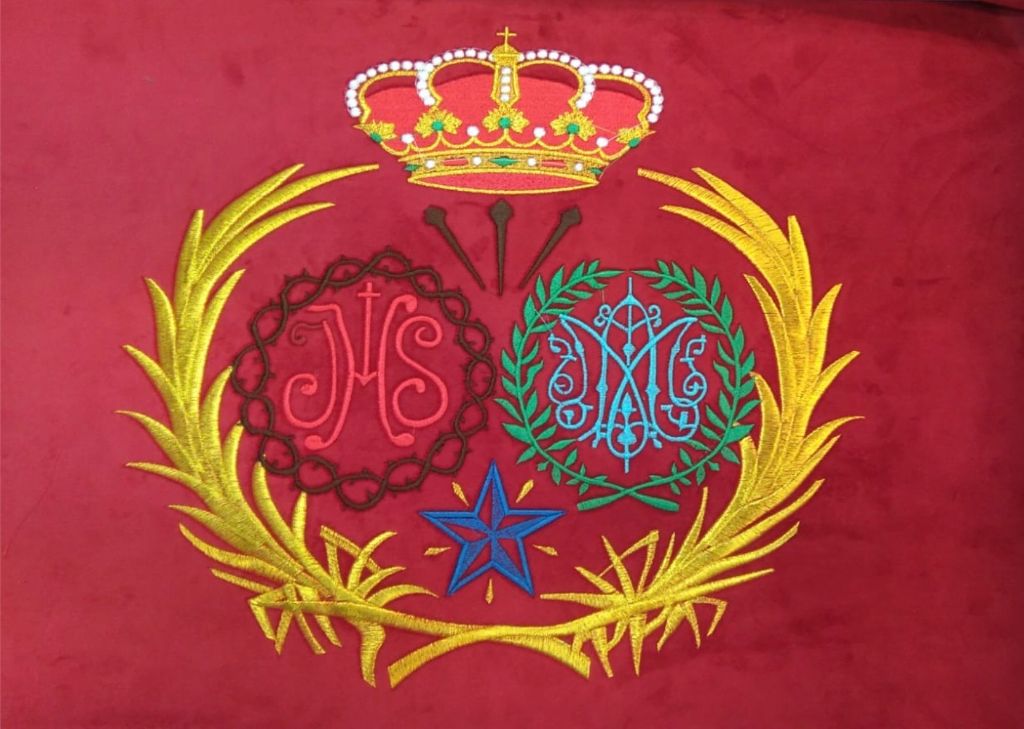 Bordado artístico escudo hermandad sobre terciopelo rojo